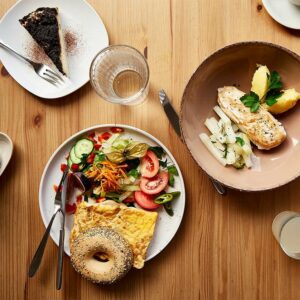 Schönes Food Foto von oben, der Fotografin Nadja Kuschel, zeigt einen gedeckten Tisch mit einem Teller mit grünem Salat und einem Bagel, belegt mit Omelette